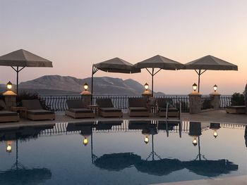 Swimming pool by sea against sky at sunset