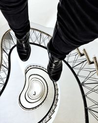 Low section of man standing on spiral staircase