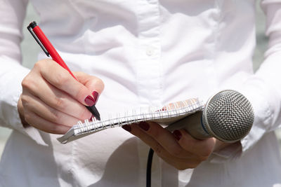 Midsection of female journalist holding microphone