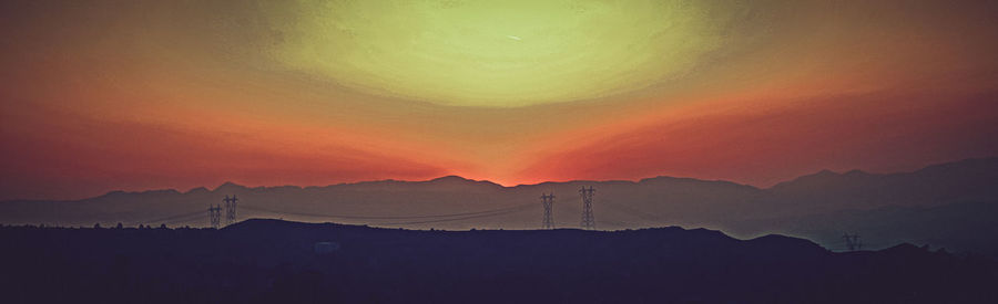 Scenic view of silhouette mountains against orange sky