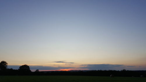 Scenic view of silhouette field against clear sky during sunset