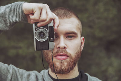 Portrait of bearded man taking photo with vintage camera