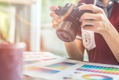Midsection of woman photographing color swatch in office