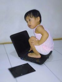 Girl using mobile phone while sitting on tiled floor