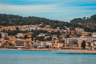 Aerial view of townscape by sea against sky