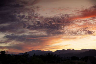 Scenic view of mountains against cloudy sky during sunset