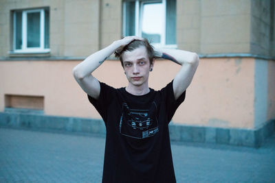 Portrait of young man standing against building on street