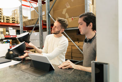 Colleagues discussing over equipment while using digital tablet at industry