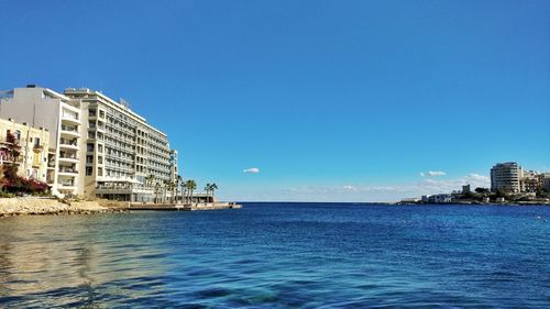 Sea by city against clear blue sky