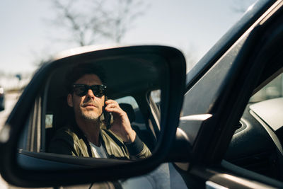 Reflection of man using smart phone in car