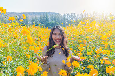 Portrait of woman standing by yellow flowering plants