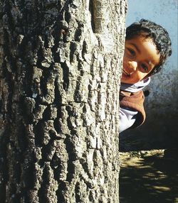 Close-up of boy leaning on tree trunk