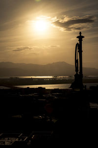 Silhouette built structure by sea against sky during sunset