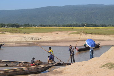 People working at shore against sky