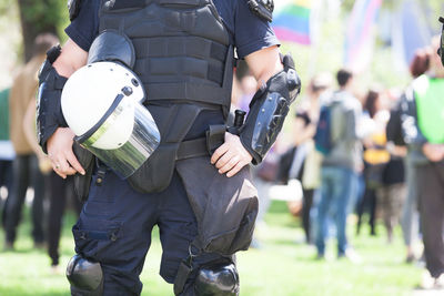 Midsection of police force against crowd during protest