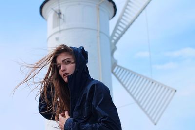 Portrait of young woman with umbrella against sky