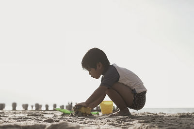 Side view of boy playing with toys at beach