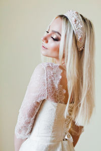 Confident woman in dress standing against wall