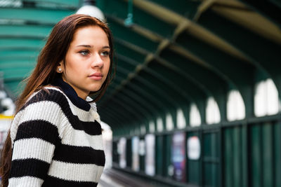 Close-up of young woman standing at railroad station