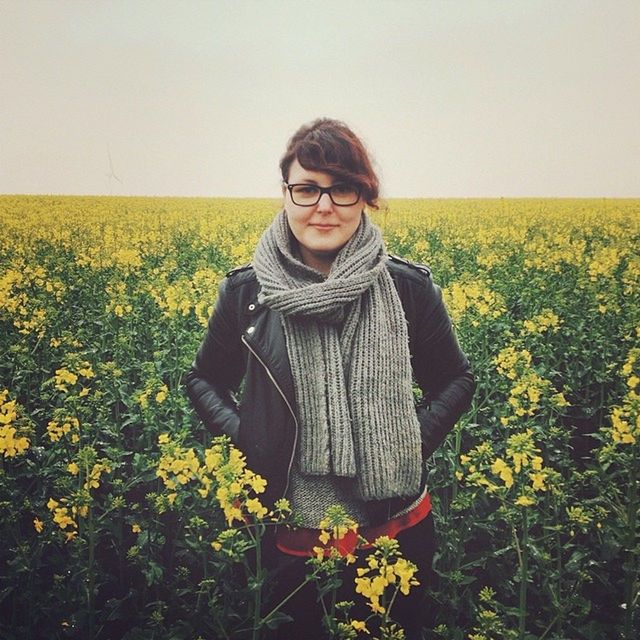 field, young adult, flower, lifestyles, casual clothing, standing, person, agriculture, young women, rural scene, leisure activity, clear sky, front view, beauty in nature, growth, plant, nature, landscape