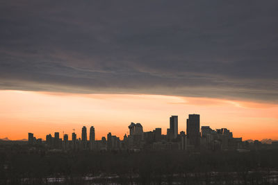Modern buildings in city against sky during sunset