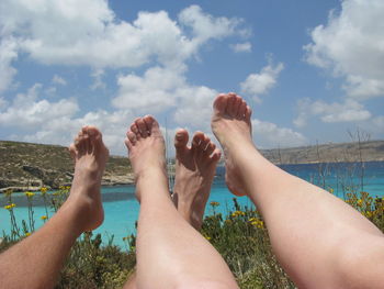 Low section of people relaxing against sky