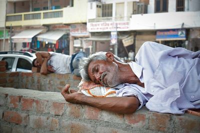 Senior homeless man sleeping on brick wall