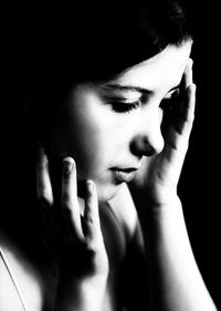 Close-up portrait of young woman against black background