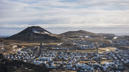 Aerial view of townscape and mountains against sky