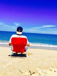 Rear view of man on beach against sky