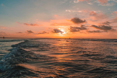 Scenic view of sea against cloudy sky during sunset