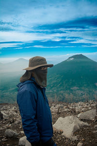 Rear view of man standing on mountain against sky