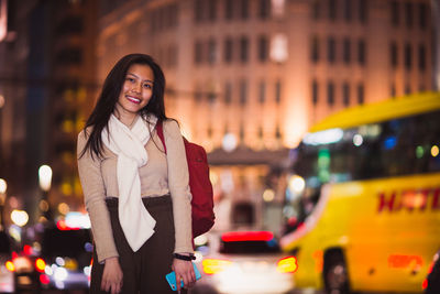 Portrait of smiling young woman standing in city