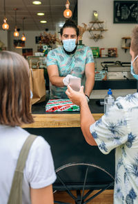 Man making contactless payment through smart phone at restaurant