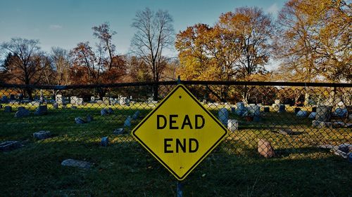 Information sign by fence at cemetery