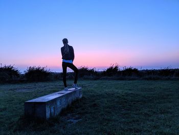 Man standing on field against sky during sunset