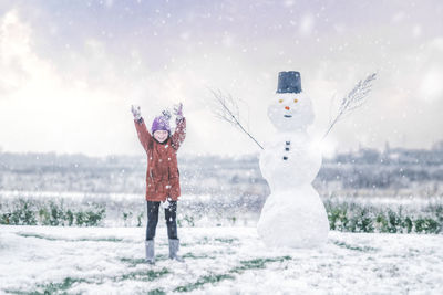 Full length of woman standing on snow covered field against sky