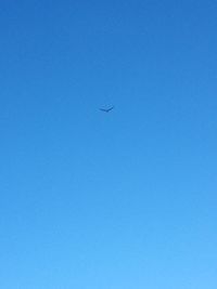 Low angle view of airplane flying against clear blue sky