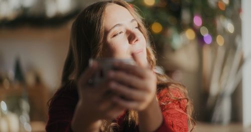 Side view of young woman blowing flowers