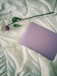 High angle view of laptop by flower on bed