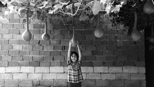 Girl holding vegetable hanging on plant