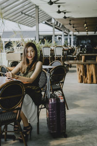 Portrait of young woman sitting on chair at outdoor cafe