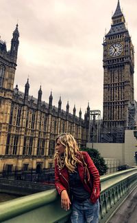 Woman standing against clock tower in city