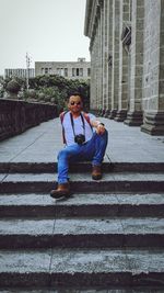 Portrait of teenage girl sitting on staircase against building