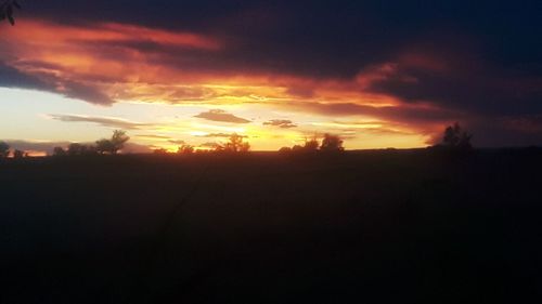 Silhouette landscape against dramatic sky during sunset