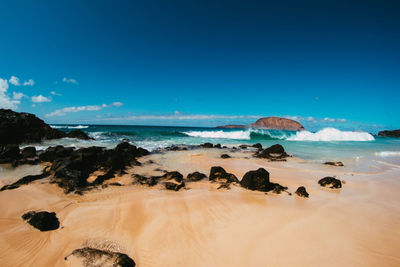 Scenic view of beach against blue sky