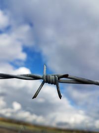 Close-up of wind turbine against cloudy sky