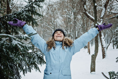 Hello winter, happy wintertime. happy young curly woman with hands raised up celebrating winter