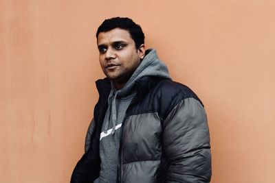 Portrait of young man standing against wall