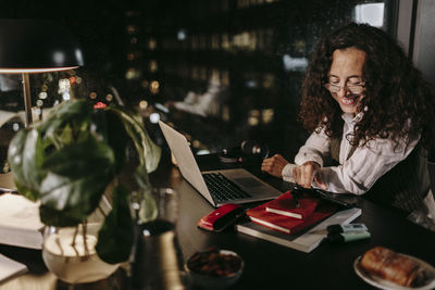 Woman using phone while sitting on table